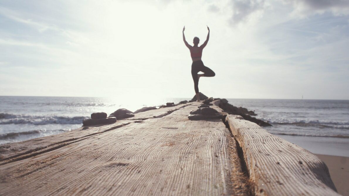 image of a lady practising yoga by the beach